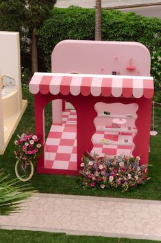 a pink and white checkered kiosk sitting on top of a lush green field