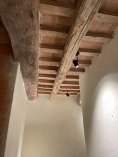 an empty room with exposed wood beams and white walls, along with a black lamp hanging from the ceiling