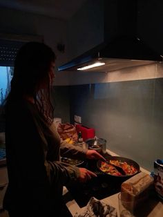 a woman is cooking in the kitchen at night