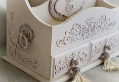 an ornate white wooden box with tassels on it