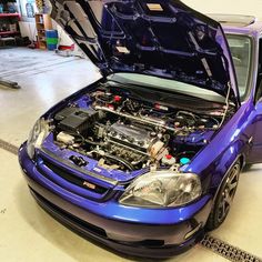 a blue car with its hood open in a garage