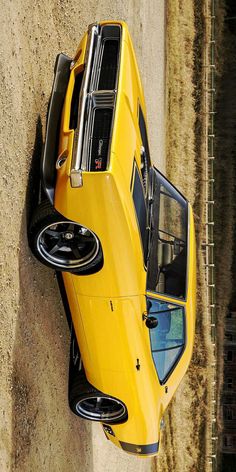 an overhead view of a yellow sports car parked on the side of a road next to a stone wall