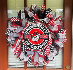 the university of georgia wreath is hanging on the front door with red, white and black ribbons