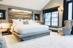 a bedroom with a large bed and white carpeted flooring in front of a window