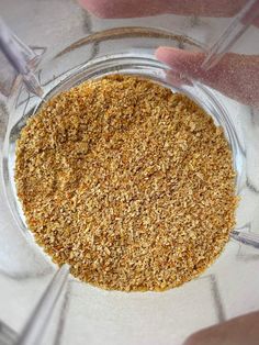 a person holding a glass bowl filled with brown sugar and other things to make it look like they are making something