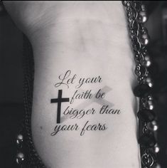 a cross tattoo on the side of a woman's stomach with words written in black ink