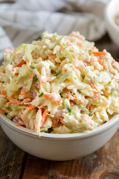 a white bowl filled with coleslaw on top of a wooden table