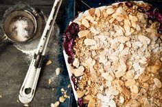 a blueberry crumbler sitting on top of a metal pan next to a spoon