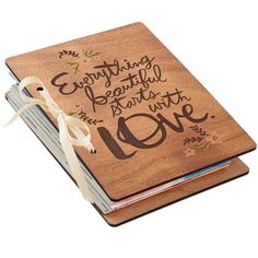 a wooden notebook with the words everything beautiful is love written on it and tied in a white ribbon