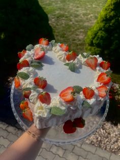 someone holding up a cake with strawberries on it