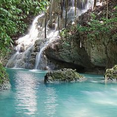 there is a small waterfall in the middle of this pool and it's blue water