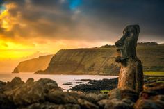 a rock formation in the foreground with a sunset behind it