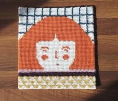 an orange and white knitted square with a woman's face on the front