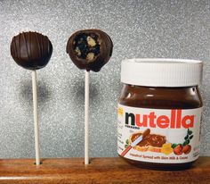 peanut butter and nutella lollipops on a wooden shelf with glitter wall behind them