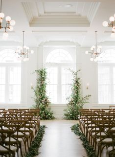 an aisle lined with wooden chairs and greenery