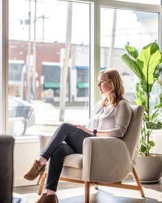 a woman sitting in a chair looking out the window