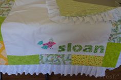 a white bed with green and yellow bedspread that says sloan on the side