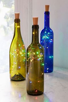 three bottles with lights in them sitting on a counter