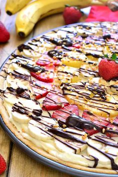 a pie with strawberries, bananas and chocolate drizzled on it