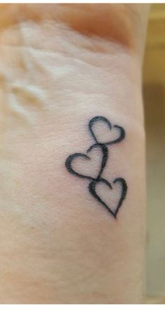 a small tattoo on the wrist of a woman with two hearts in the shape of a heart