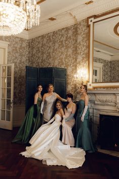 a group of women standing next to each other in front of a mirror and fireplace