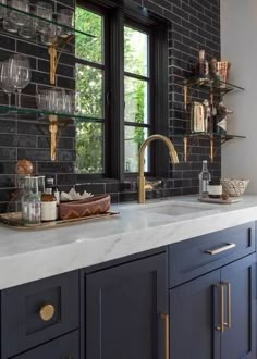 a kitchen with black brick walls and white counter tops, gold accents on the faucet