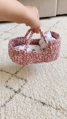 someone is holding a crocheted basket on the floor