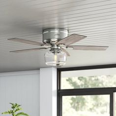 a ceiling fan that is hanging from the ceiling in a room with white walls and windows