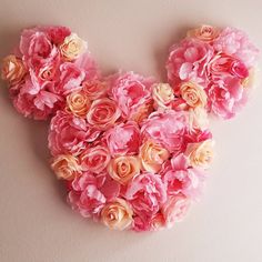 pink flowers are arranged in the shape of mickey mouse's head on a white wall