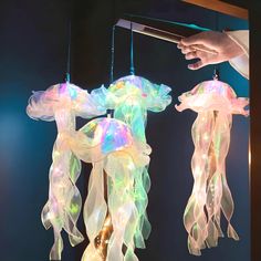 two jellyfish shaped lights hanging from strings in front of a person's hand