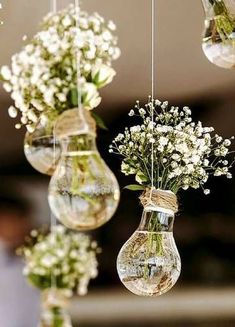 three hanging vases filled with white flowers and greenery are suspended from the ceiling