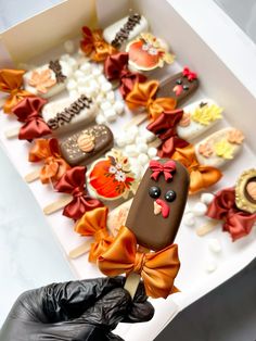 a box filled with lots of different types of cookies on top of a table next to black gloves