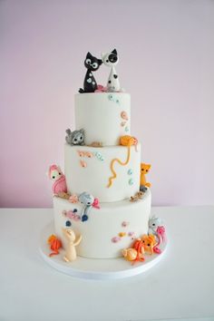 a three tiered cake decorated with cats and kittens on it's sides