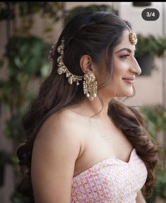 a woman in a pink dress with gold jewelry on her head and one ear ring