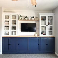 a living room with blue cabinets and a flat screen tv mounted on the wall above it