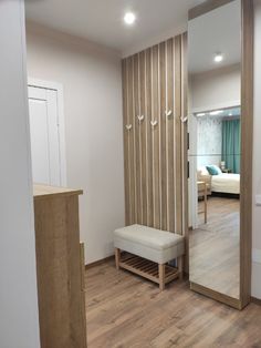 a white bench sitting in the middle of a living room next to a mirror and door