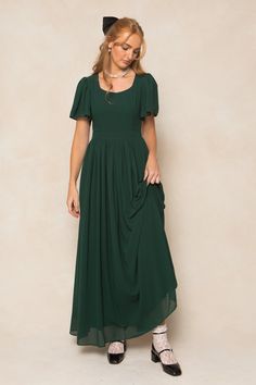 Twirl in style with the Abbie Dress in Emerald Chiffon. The flowy chiffon fabric and subtle sweetheart neckline provide a romantic touch, while the short bell sleeves and maxi-length skirt with functional pockets add a playful twist. This dress is not only the ultimate fall bridesmaids silhouette, but perfect for date night, special events, church and more. With a hidden back zipper, princess seams on the bodice and full lining, you simply can't go wrong. This women's dress is available in up to Dark Green Modest Dress, Lotr Bridesmaid Dresses, Eucalyptus Dress, Green Wedding Party, Flowy Long Dress, Dark Green Bridesmaid Dress, Short Bell Sleeves, Modest Formal Dresses, Fall Bridesmaids