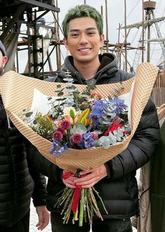 a man with green hair holding a bouquet of flowers in front of two other men