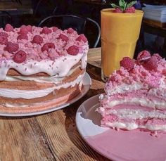 there is a large cake with raspberries on it and a drink next to it