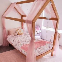 a pink canopy bed in a girls bedroom