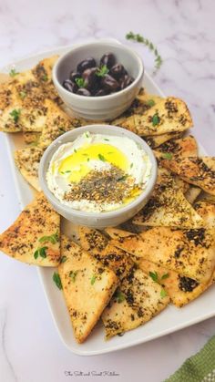 an appetizer plate with pita chips and olives