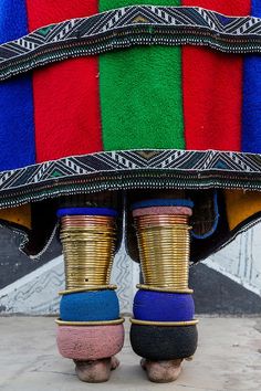 the legs of two people wearing brightly colored shoes and carrying baskets on their heads are covered by colorful blankets