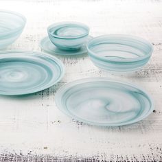 four blue glass bowls sitting on top of a table