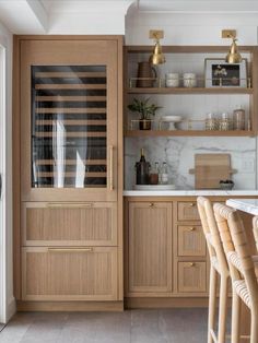 a kitchen with wooden cabinets and white marble counter tops, along with bar stools