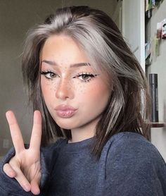 a woman with freckles on her face making the peace sign for the camera