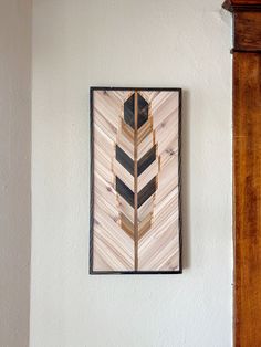 a painting hanging on the wall next to a wooden frame with an arrow in it