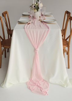 the table is set with white and pink linens, silverware, and flowers