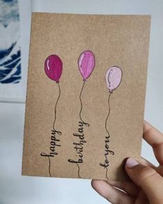 a hand holding up a card with three balloons on it, and the words happy birthday written in cursive writing