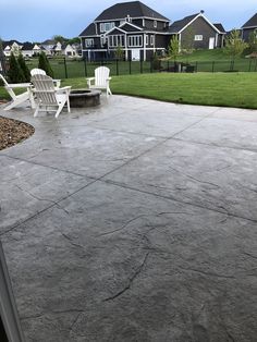 an outdoor patio with two white chairs and a fire pit in the middle of it