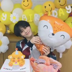 a person sitting at a table with some balloons in the shape of animals and cats